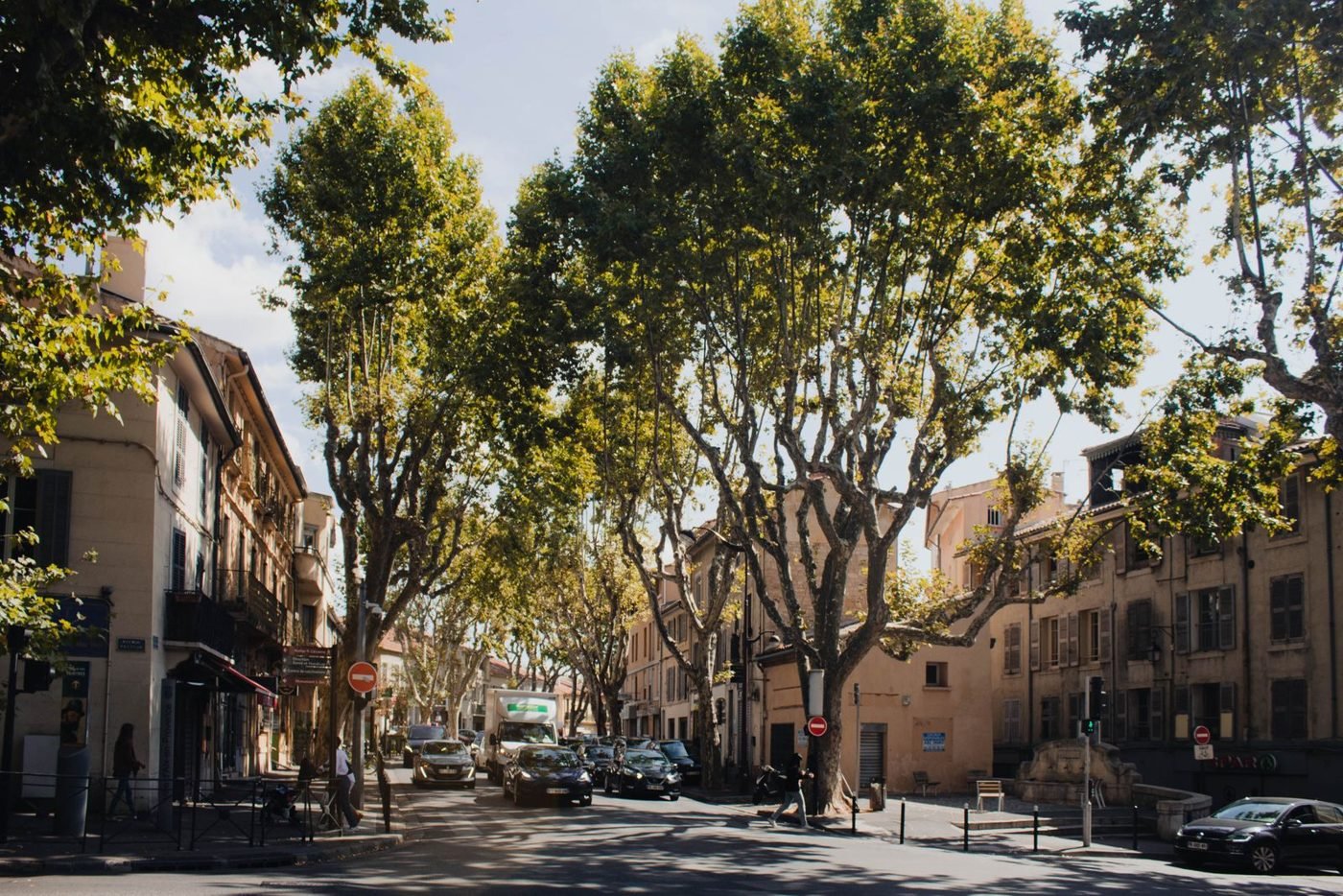 Rue ensoleillée à Aix-en-Provence avec des arbres et des bâtiments historiques