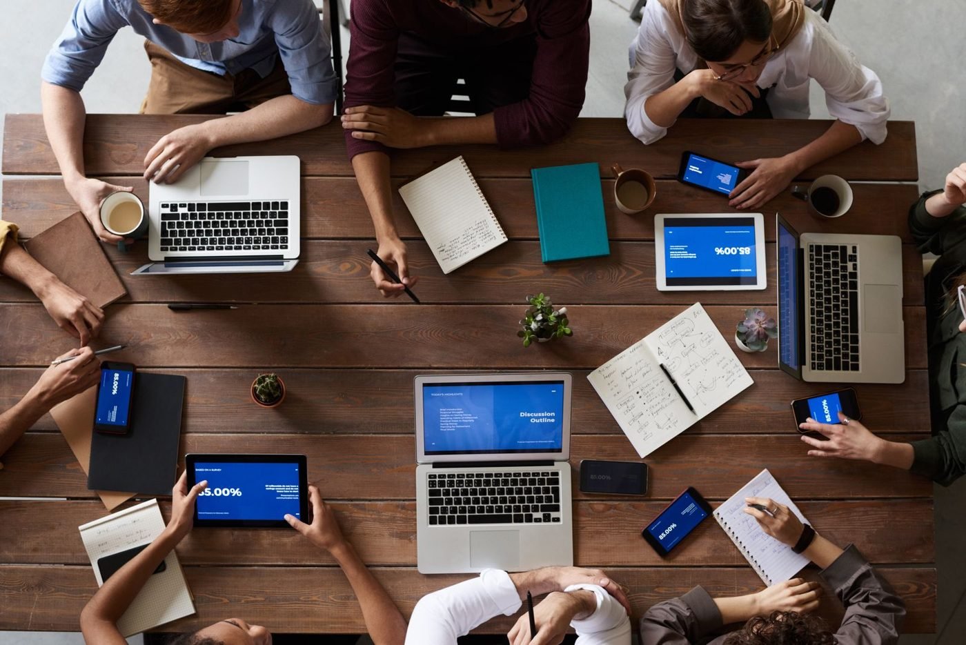 Équipe réunie autour d'une table de travail avec ordinateurs et carnets