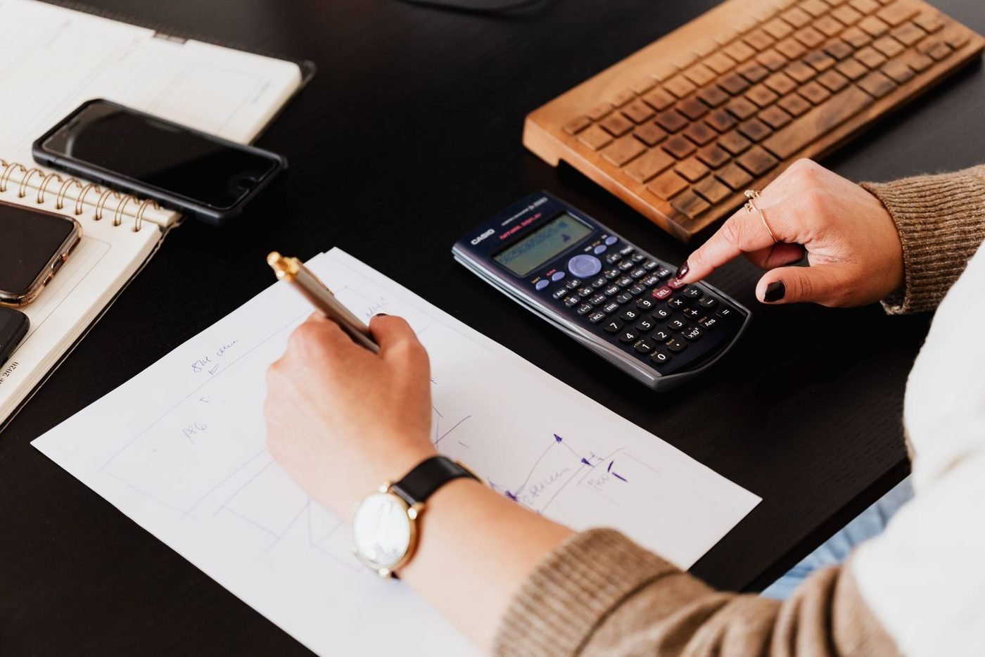Créateur d'entreprise vérifiant ses calculs à la calculatrice sur un bureau