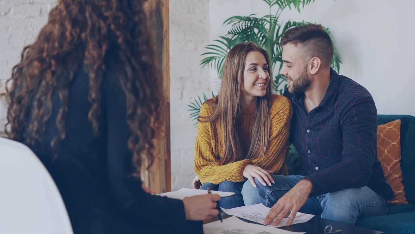 Jeune couple discutant de projets avec un conseiller dans un bureau