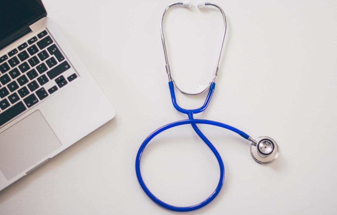 Stéthoscope et ordinateur portable sur un bureau blanc