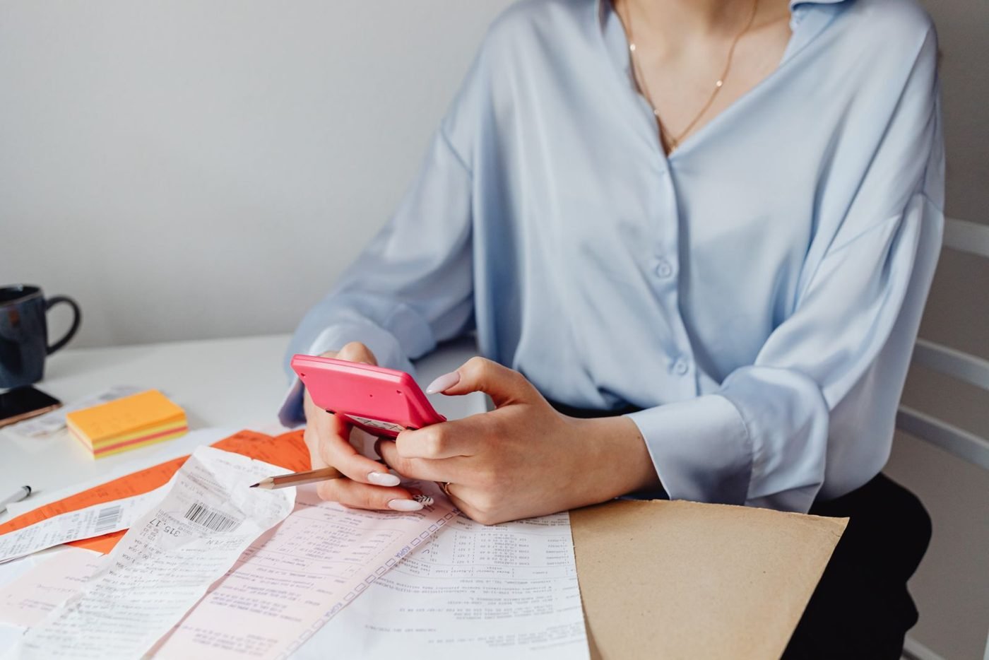 Femme utilisant une calculatrice entourée de factures sur un bureau