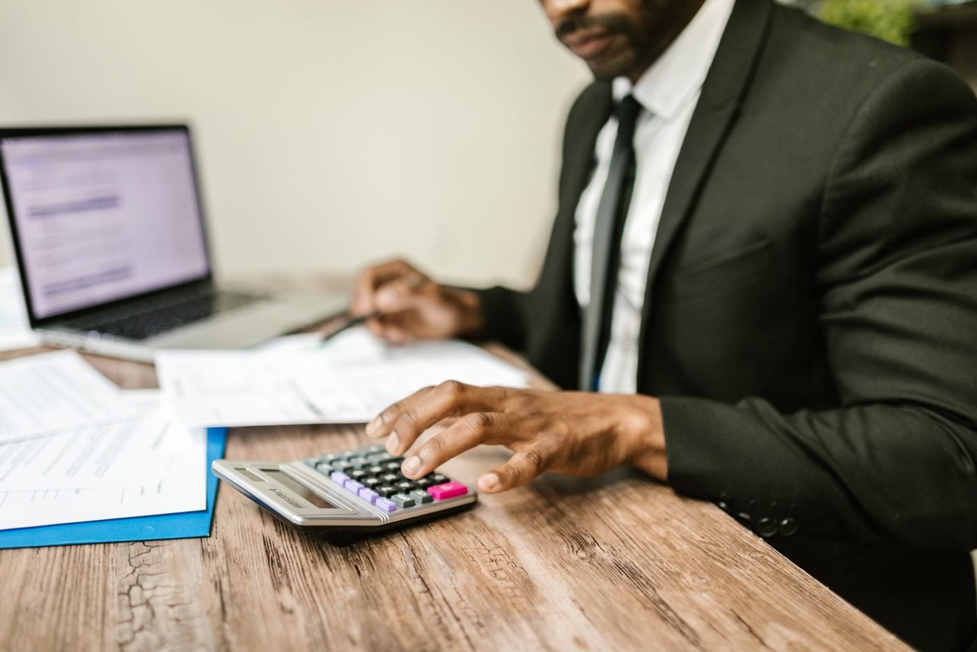 Homme d'affaires utilisant une calculatrice avec des documents financiers
