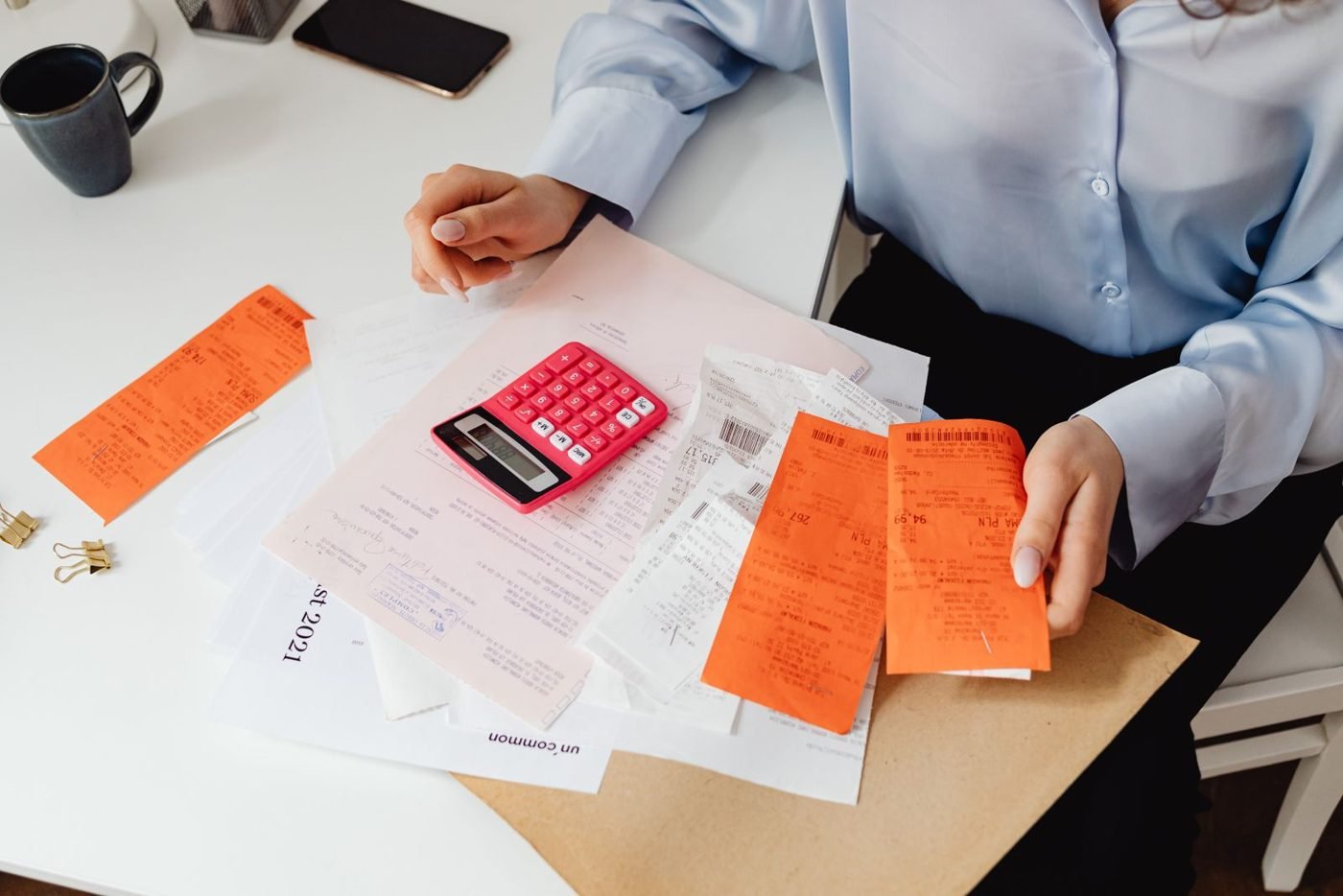 Femme calculant ses dépenses avec des documents et une calculatrice