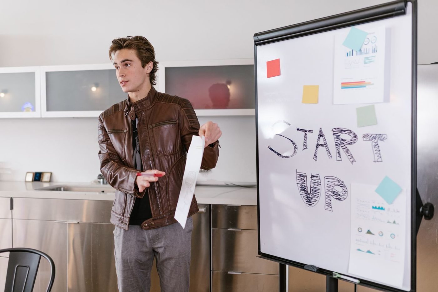 Jeune entrepreneur présentant son projet devant un paperboard