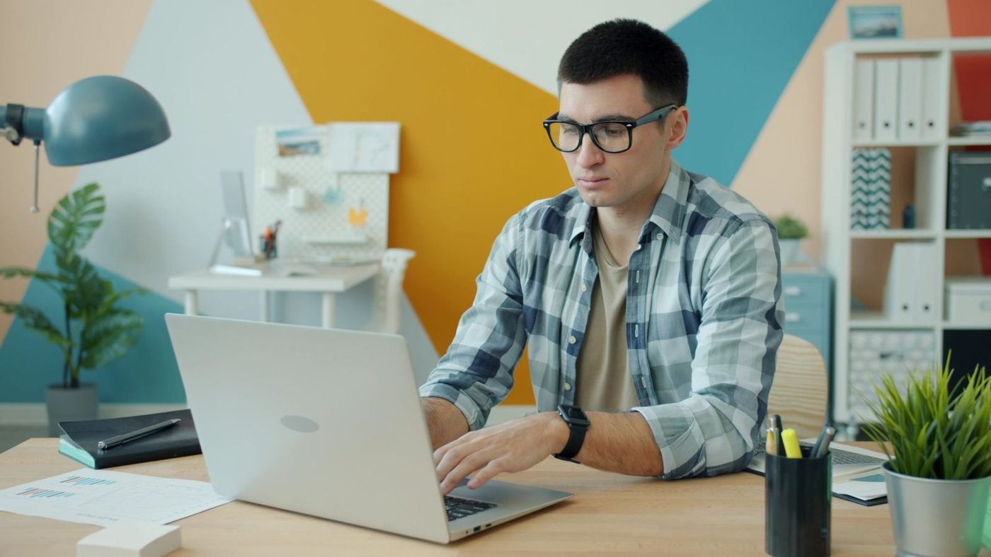 Jeune homme concentré travaillant sur un ordinateur portable dans un bureau