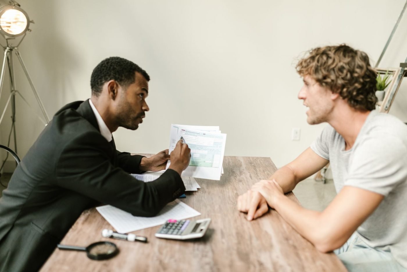 Un conseiller financier discute de documents avec un client à son bureau